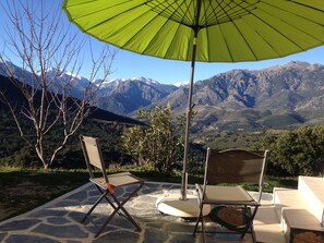 A patio with two chairs and a green umbrella, overlooking a mountainous landscape. - EAGLE'S NEST - 2-Bedroom Apartment (Tralonca)