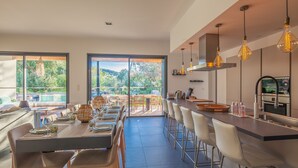 A modern kitchen with a large island, bar stools, and pendant lighting. - Incredible 5* villa near Cala Rossa (Porto-Vecchio)