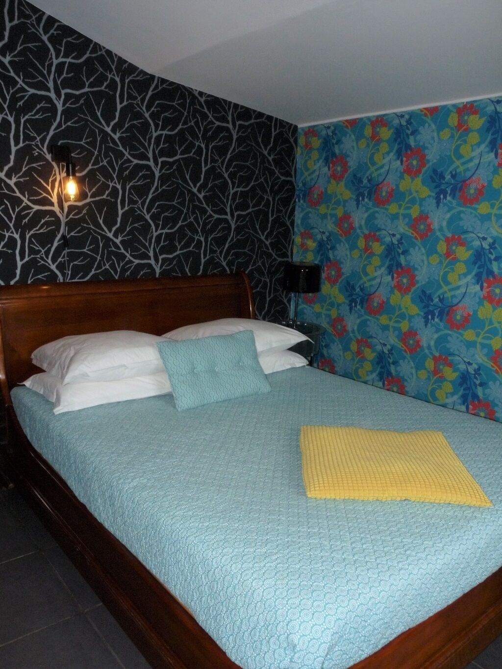 Ein Bett mit einer blauen Steude, einer gelben Decke und weißen Kissen.