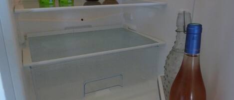 An open refrigerator with two boxes of 'Pressade bio' juice, two bottles of dark liquid, and a bottle of red liquid with a blue cap.