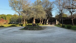 A gravel driveway leading to a gated entrance surrounded by trees and shrubs. - Drôme provençale, nature, outdoor swimming pool and spas  (La Baume-De-Transit)
