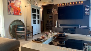 A living room with a TV, a cabinet, a chair, and a coffee table with decorative items. - Drôme provençale, nature, outdoor swimming pool and spas  (La Baume-De-Transit)