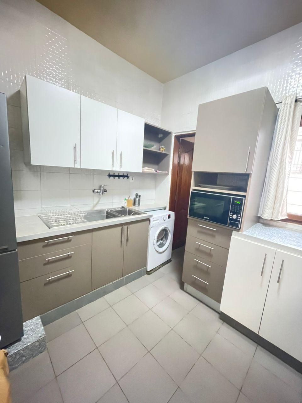 Cocina compacta con lavadora, microondas y pileta.
