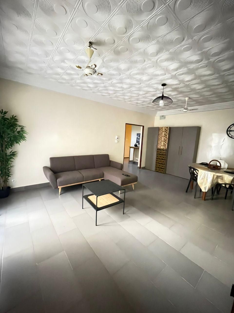 A spacious living area with a sectional sofa, a coffee table, and a dining table with chairs.