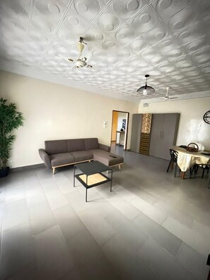 A spacious living area with a sectional sofa, a coffee table, and a dining table with chairs. - APPARTADAKAR F5 for rent Cité-Batrain - MERMOZ- OUAKAM-DAKAR (Dakar)