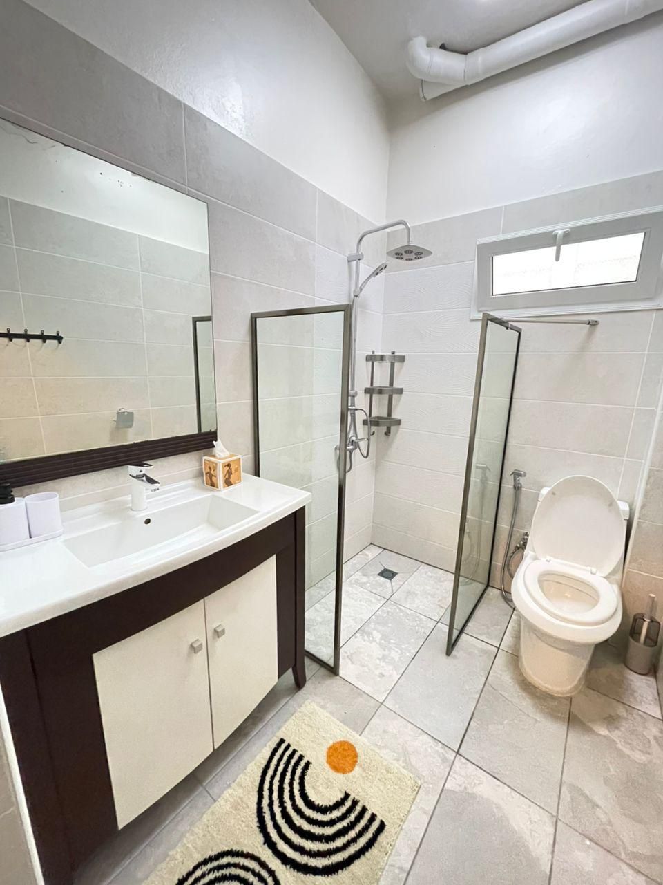 Un baño con un lavabo blanco, un inodoro, una cabina de ducha de vidrio y un espejo.
