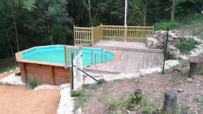 Un bain à remous avec une terrasse en bois et un mur en pierre.