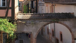 A narrow cobblestone street with traditional half-timbered houses, an archway, and a bicycle parked under a sign.