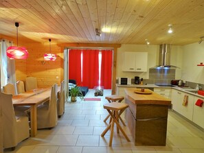 Une cuisine moderne avec des meubles en bois, une hotte en acier inoxydable et un coin repas comprenant une table et des chaises en bois.