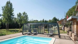 A swimming pool with a glass enclosure and lounge chairs. - Private swimming pool, Jacuzzi and Sauna Clair de Lune 4****  (Uzemain)