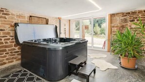 A spa area with a hot tub, wooden benches, and a potted plant. - Private swimming pool, Jacuzzi and Sauna Clair de Lune 4****  (Uzemain)