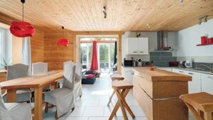 A modern kitchen with wooden cabinets, a central island, and red pendant lights. - Private swimming pool, Jacuzzi and Sauna Clair de Lune 4****  (Uzemain)