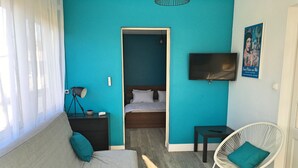 A room with a bed, a sofa, a TV, and a chair.
