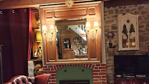 A cozy living room with a fireplace, leather armchair, and a coffee table with remote controls.