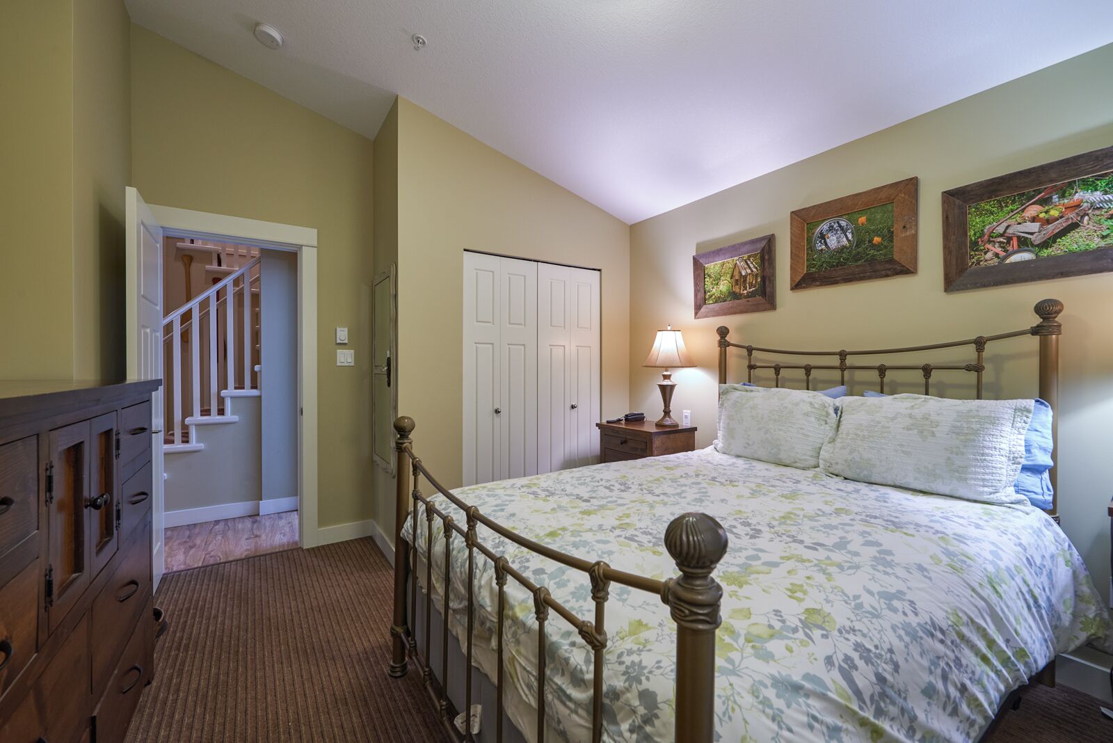 Un dormitorio con cama, cómoda y escalera que conduce a otra habitación.