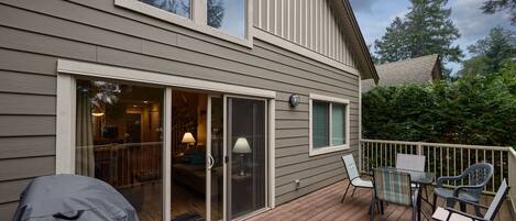 A deck with outdoor furniture, a sliding glass door leading to an interior room, and a covered grill.