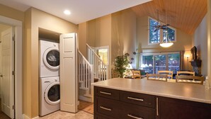 A kitchen with a built-in washer and dryer, a wooden staircase, and a dining area with chairs and a table. - 3 bed 2 bath, Wifi, Cable, Pool/Hot Tub, BBQ, Mini Golf, Beach, license#00005785 (Parksville)