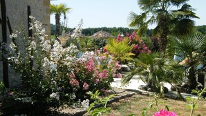 A garden with various flowering plants and a stone building. - Superb gîte with private heated pool, air-conditioned rooms  (Pomport)