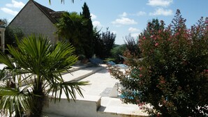 A courtyard with a stone building, palm trees, and a pool area. - Superb gîte with private heated pool, air-conditioned rooms  (Pomport)