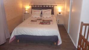 Una habitación con paneles de madera, una cama, dos lámparas de noche y una mesita de noche con lámpara.