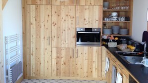 Eine Küche mit Holzausstattung, einem Einbauofen, einer Spüle und einer Pendelleuchte.