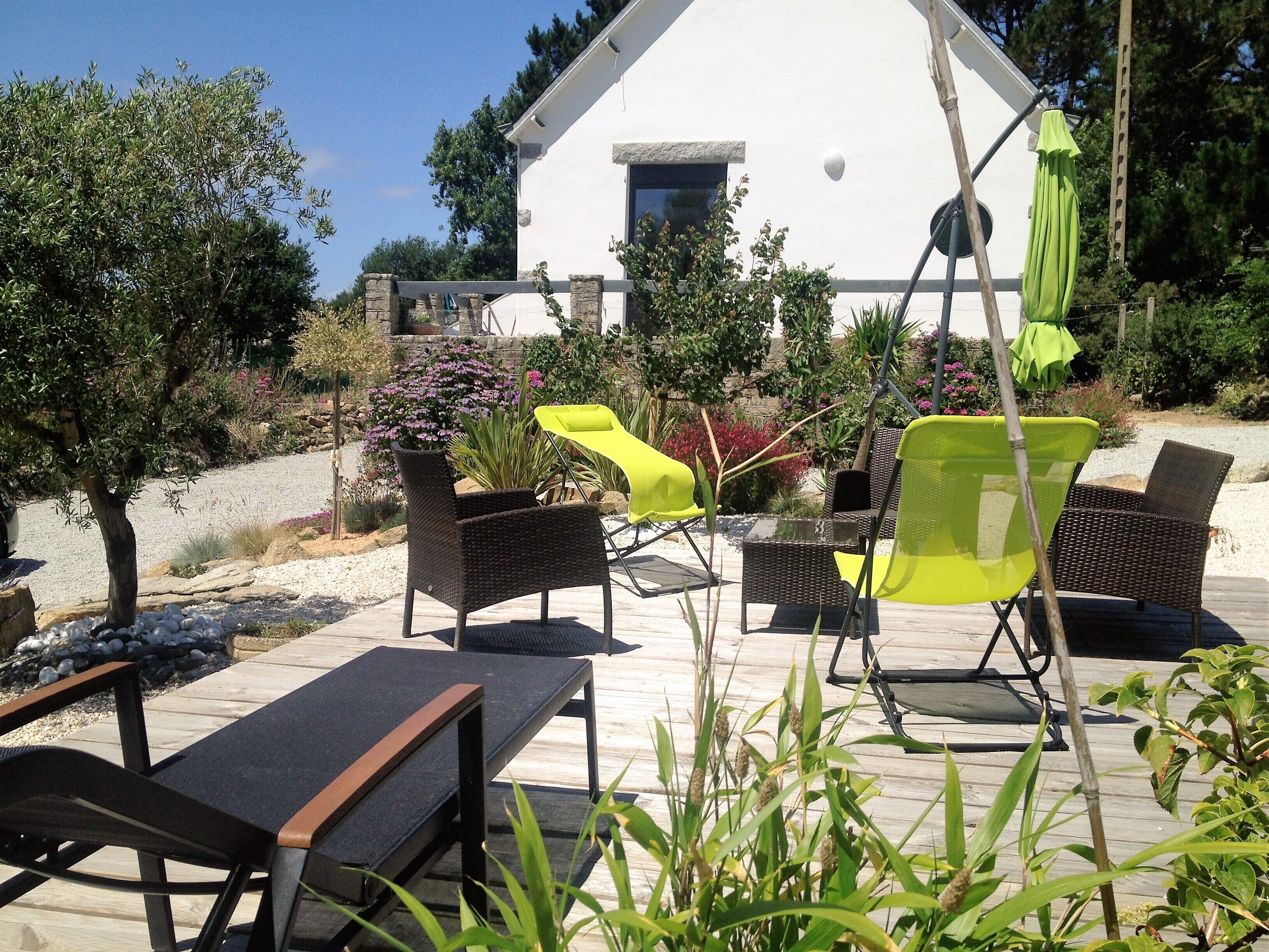 An outdoor patio with wicker furniture, a table, and a white building in the background.