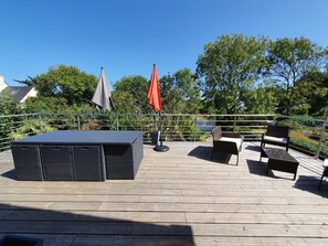 A wooden deck with outdoor furniture, including a table and chairs, and two umbrellas. - independent house in bigouden country (Névez)