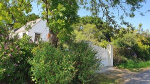 A white building with a sloped roof, surrounded by dense greenery and a white fence.