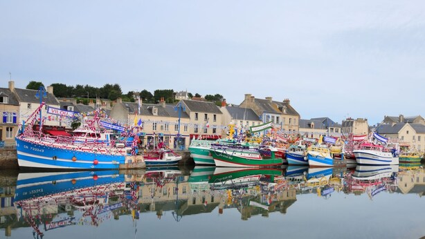 Un port où plusieurs bateaux sont amarrés, et dont le reflet se mire dans l’eau calme.