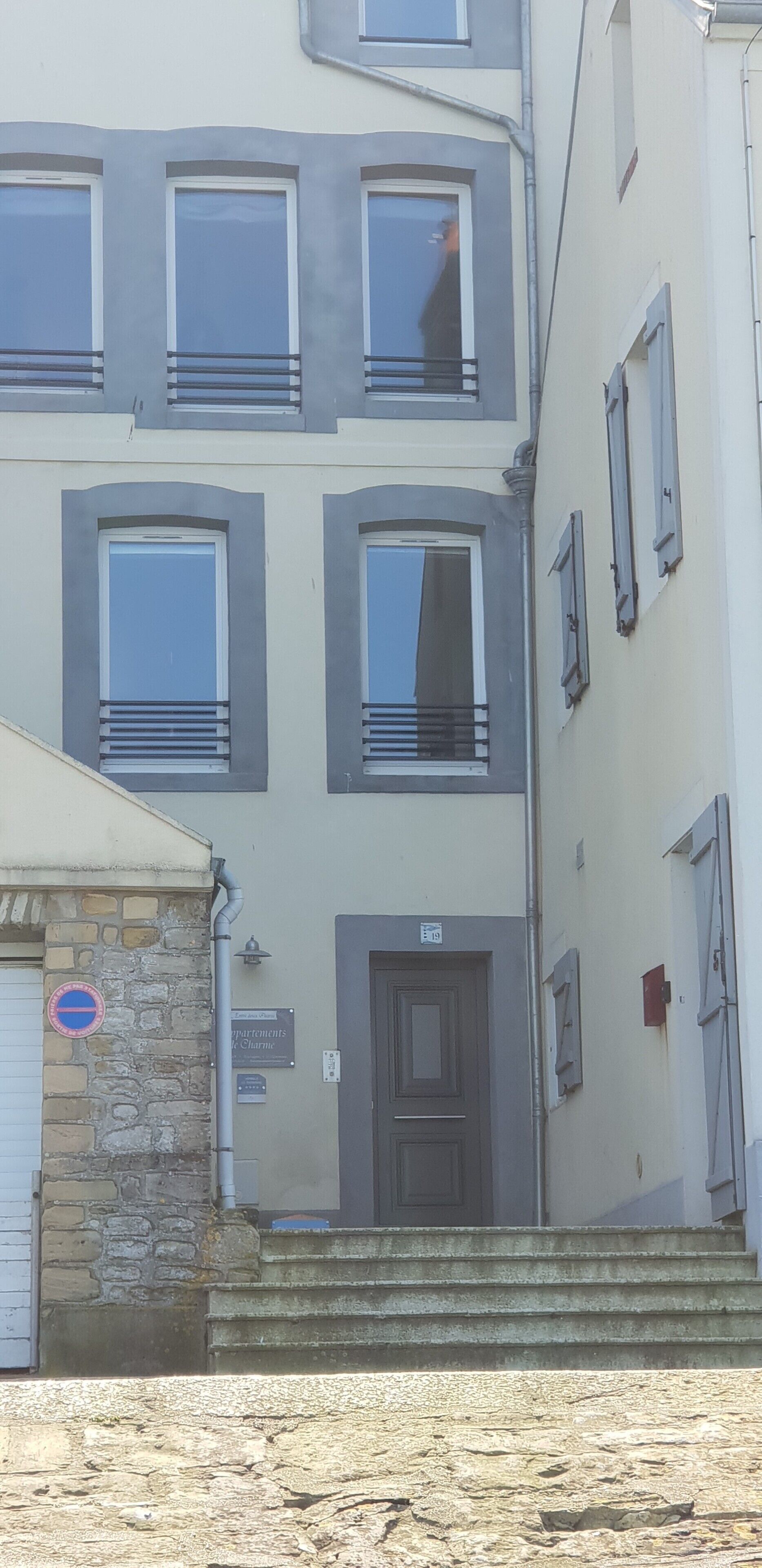 A multi-story building with a stone facade, a door marked '9', and a 'No Parking' sign.
