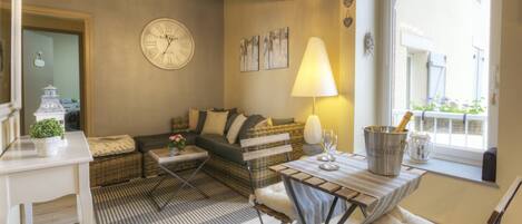 A cozy living room with a sofa, a dining table, and a lamp.