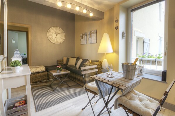 A cozy living room with a sofa, a dining table, and a lamp.