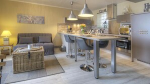 Une cuisine moderne dotée d’un îlot central, de tabourets de bar, de luminaires suspendus et d’un réfrigérateur.