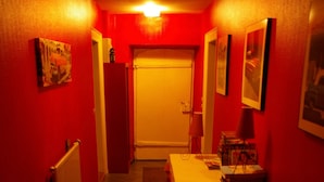 A narrow hallway with red walls, a radiator, a table with chairs, and framed pictures on the walls. - Apartment 6-10 p, quiet, close to resorts and nature, Wifi, cleaning and sheets included (Fellering)