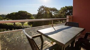 An outdoor balcony with a table and chairs, overlooking a garden and trees. - Comfortable T2 Beach/Pool/Golf/Thalasso (Anglet)