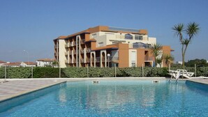 A modern hotel with a swimming pool, surrounded by greenery and palm trees. - Comfortable T2 Beach/Pool/Golf/Thalasso (Anglet)