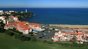 A coastal hotel with multiple buildings, a parking lot, and a beach view. - Comfortable T2 Beach/Pool/Golf/Thalasso (Anglet)