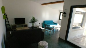 Un salon moderne avec un canapé, une table basse, une plante en pot et un téléviseur.