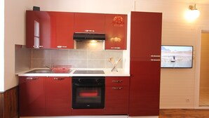 A kitchen with red cabinets, a black oven, and a tiled backsplash.