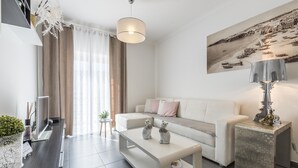 Un salon moderne avec un canapé blanc, une table basse et une table d’appoint sur laquelle se trouve une lampe.