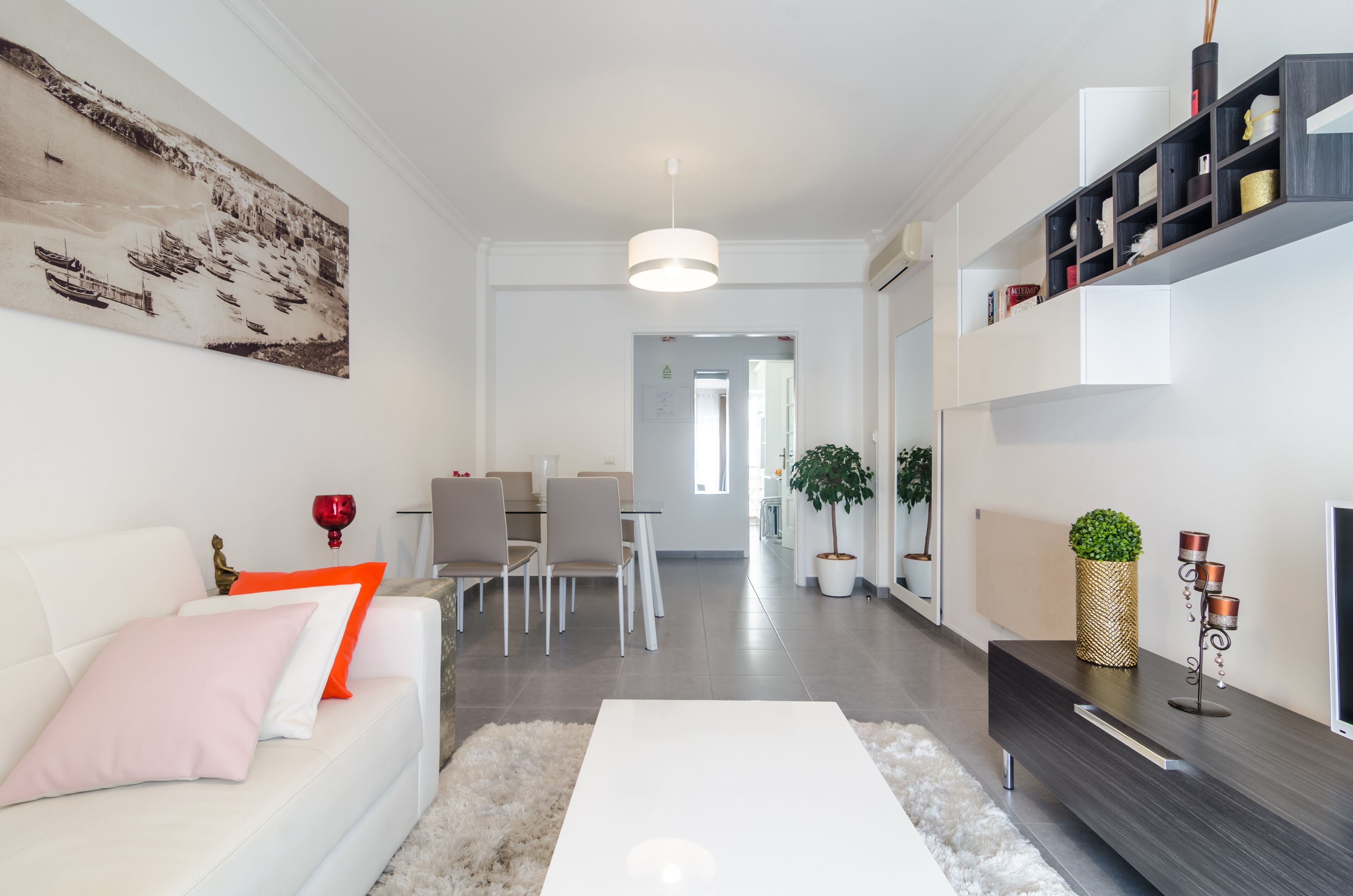 En moderne stue med en hvid sofa, et sofabord og et spiseområde med stole og et bord.