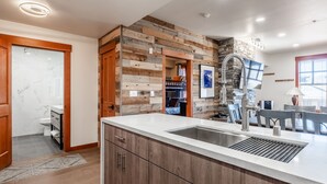 Une cuisine moderne avec un mur d’accent en bois, un évier intégré et un coin repas comprenant une table et des chaises.
