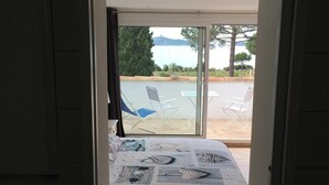 A bedroom with a bed, a window, and a view of an outdoor area with chairs and a table.