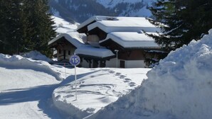Un chalet enneigé, avec une piste de ski en arrière-plan.