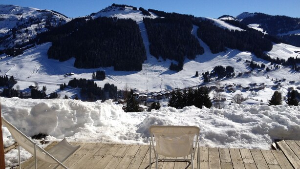 Un paysage de montagne enneigé avec une terrasse en bois et une chaise.