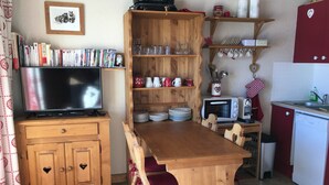 Une cuisine chaleureuse avec des meubles en bois, une table à manger et un téléviseur.