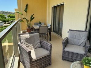 A balcony with wicker chairs, a dining table, and a potted plant. - Fantastic apartment for lovers, friends or family vacations (Albufeira)