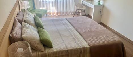 Une chambre à coucher bien rangée, avec un lit, des oreillers, une lampe de chevet, un bureau avec un miroir et une chaise.