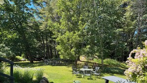 Un jardin bien entretenu, avec un chemin de pierres menant à un espace de détente agrémenté de tables et de chaises.
