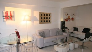 Ein modernes Wohnzimmer mit einem Glastisch, einem weißen Sofa und einem Glastisch für Essbereich.